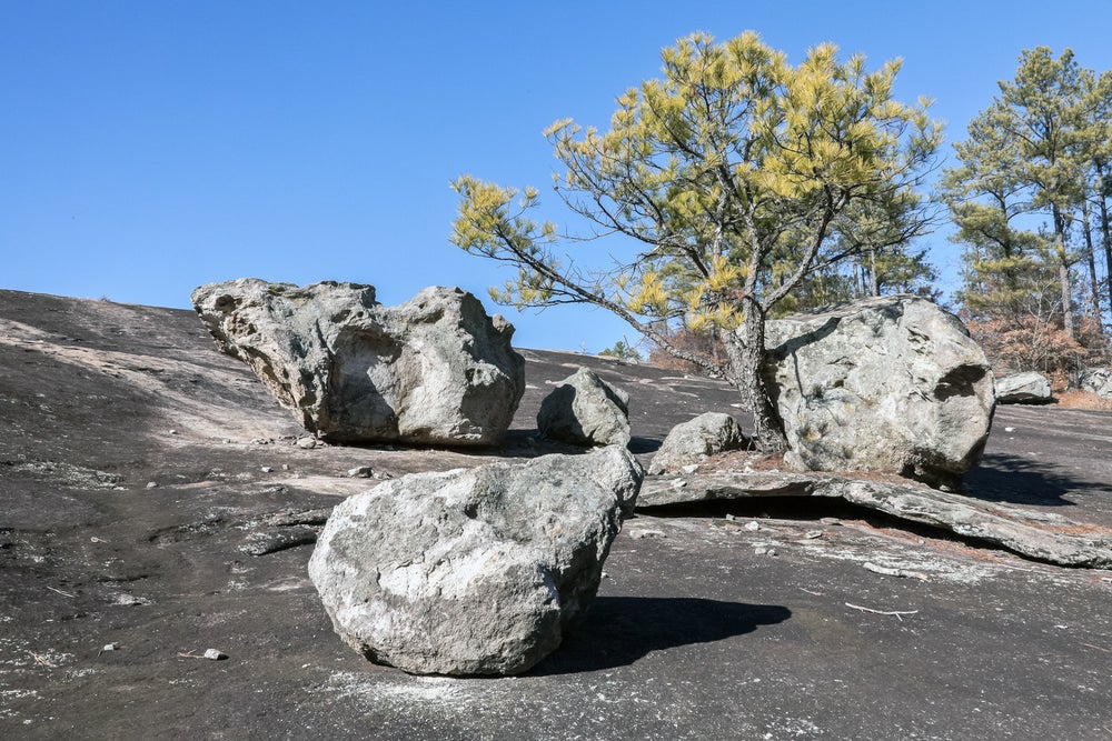 granite stones rest on an outcropping near trees on a mountain