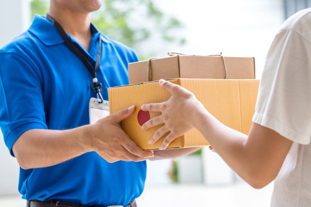 a postal worker handing a woman mail forwarded from elsewhere