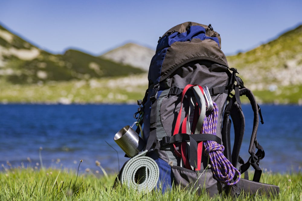 a bag full of hiking and camping gear near the edge of a lake