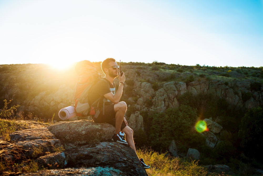 Man talking on walkie talkie with nature in background 