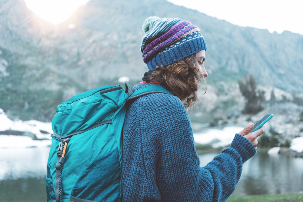 Female hiker using her smartphone in a snow covered landscape.