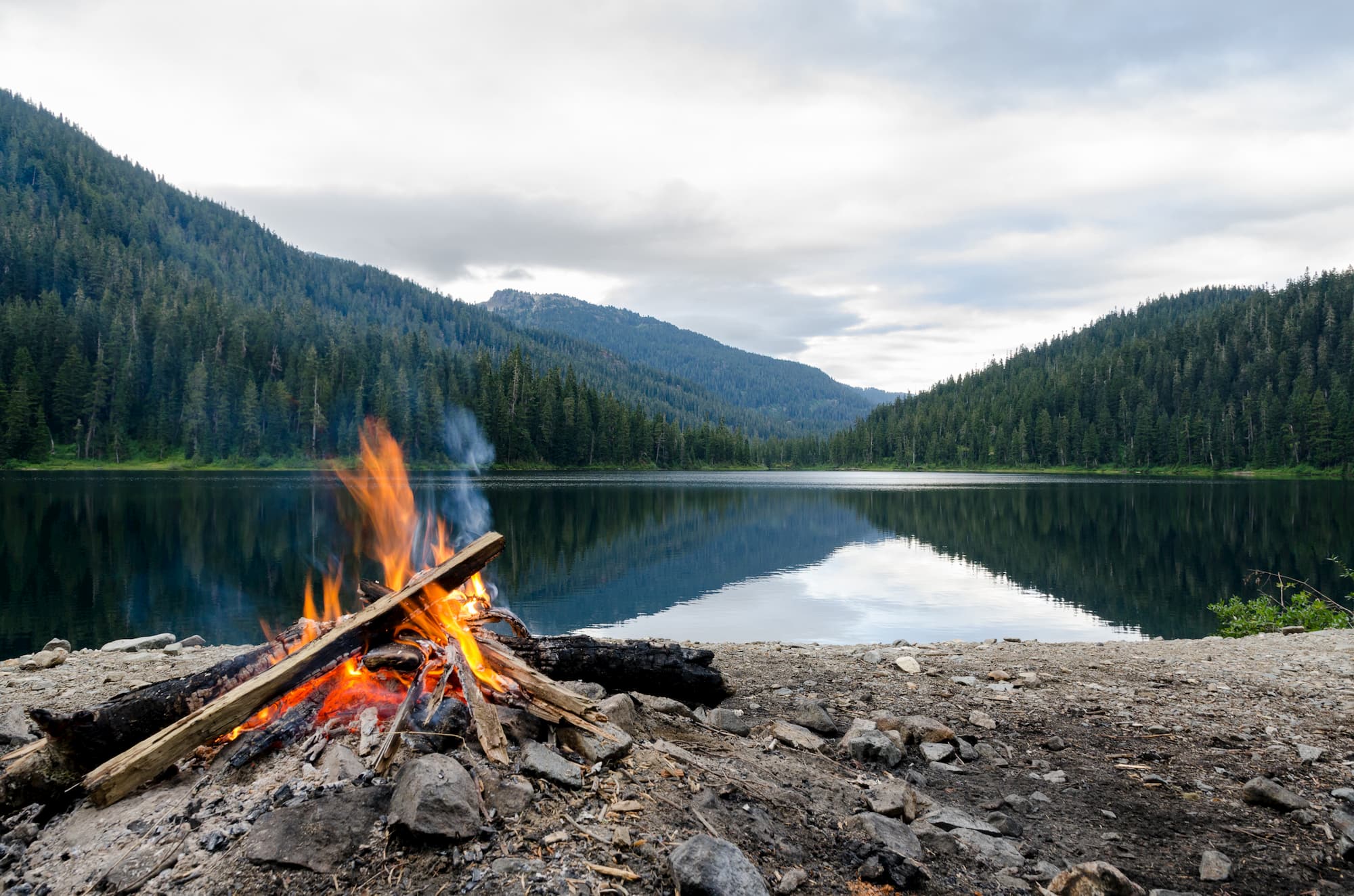 a campfire set up on the shore of a lake