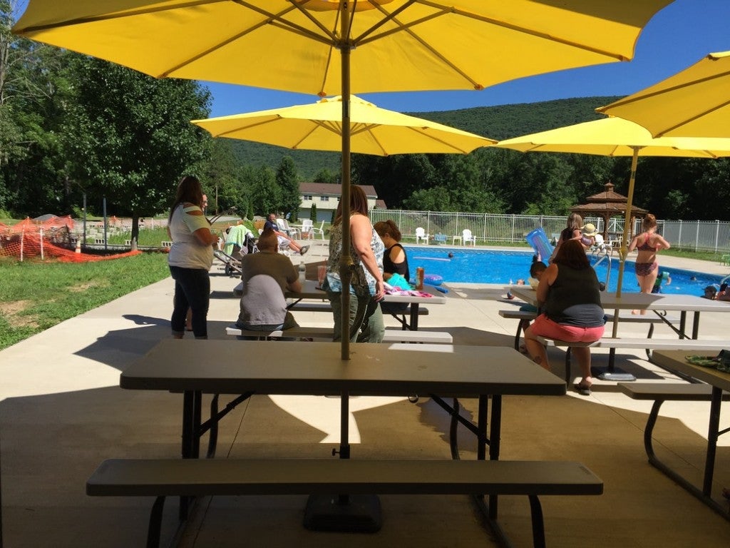 a family sits at picnic tables near a pool