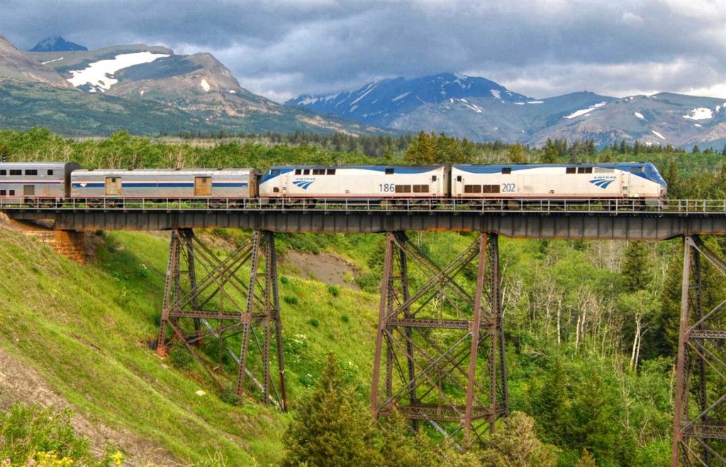 view of train to glacier in the distance as it crosses elevated bridge over green valley