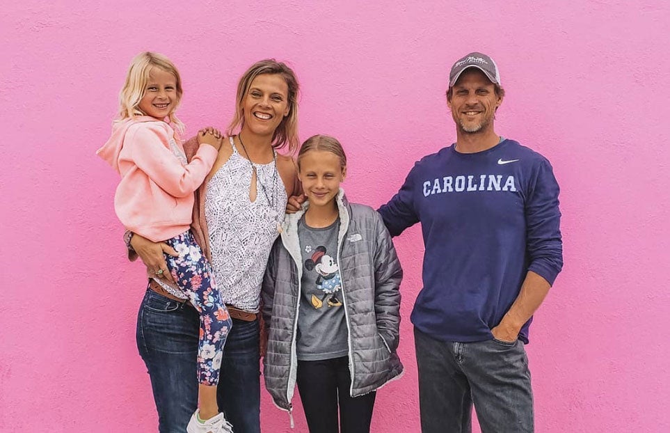 a family of four in front of a pink wall