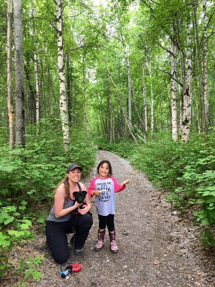 a child and her mother on a hiking trail holding a puppy