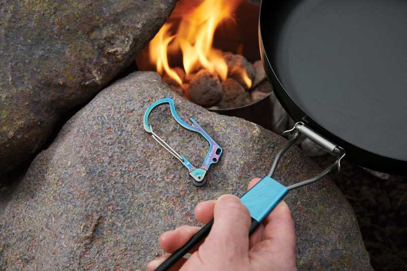  a firebiner sitting on a rock near a campfire and a pan