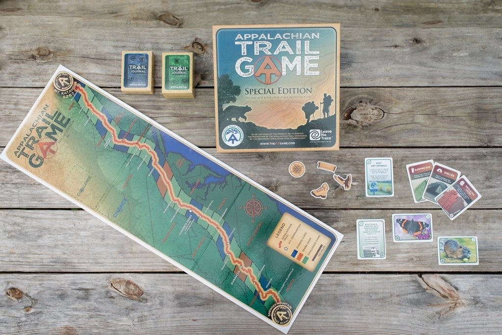 a wooden table set up with the Appalachian trail game cards and a map