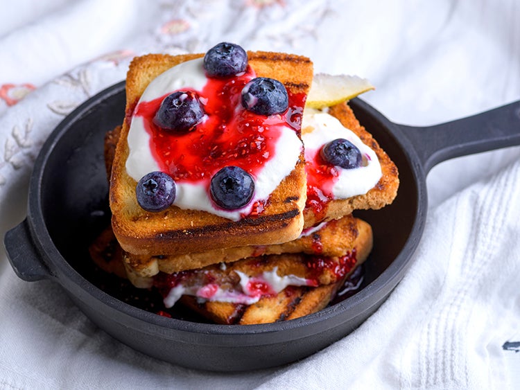 french toast stacked in a cast iron skillet and covered in berries