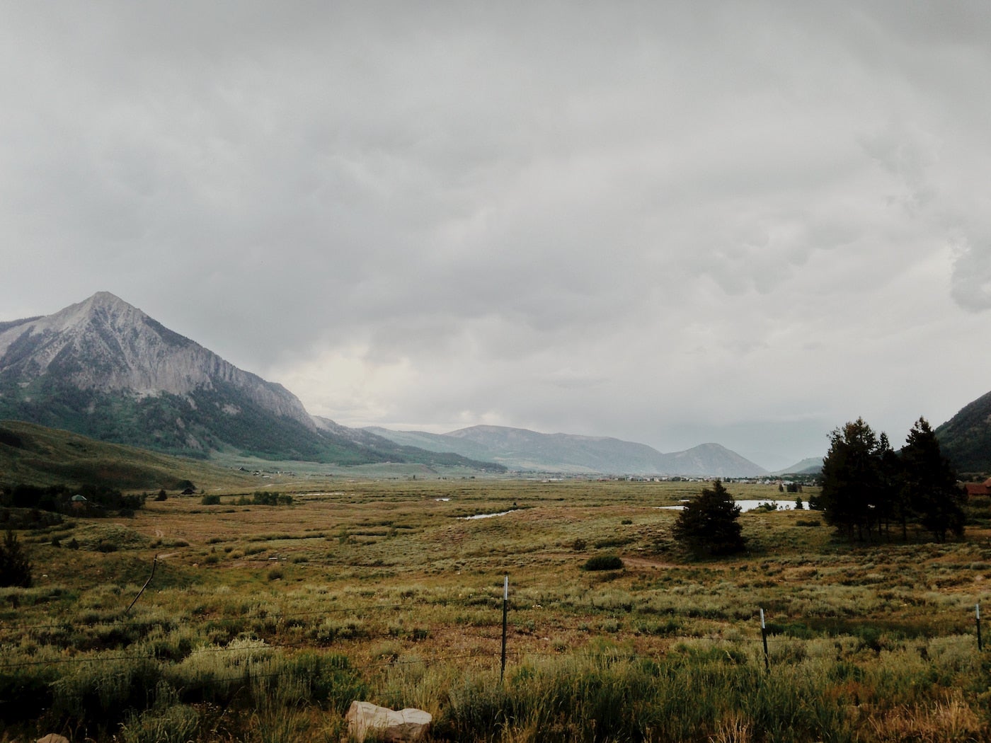 Fields of yellowed grass in plains below a mountain.