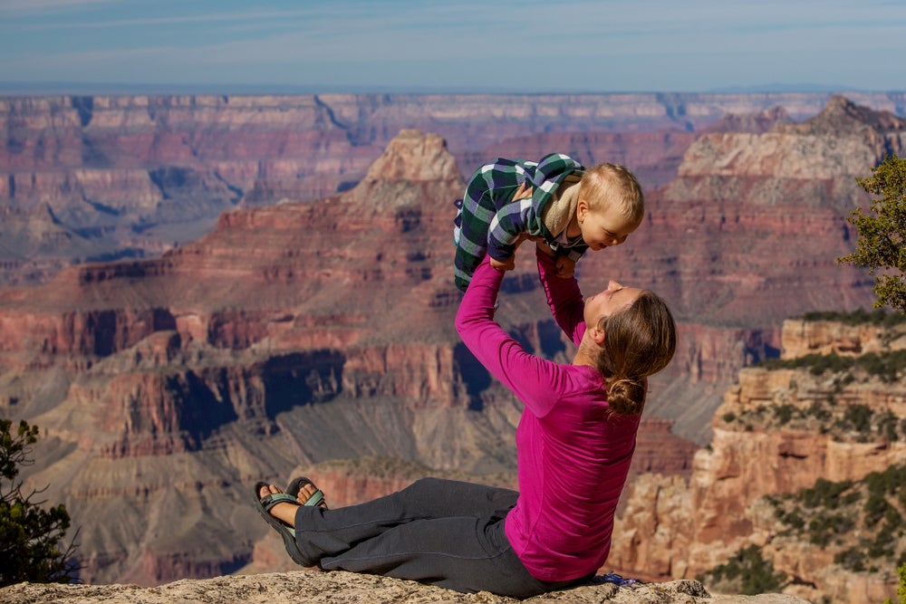 Mother lifting her son up in the air with The Grand Canyon in background 