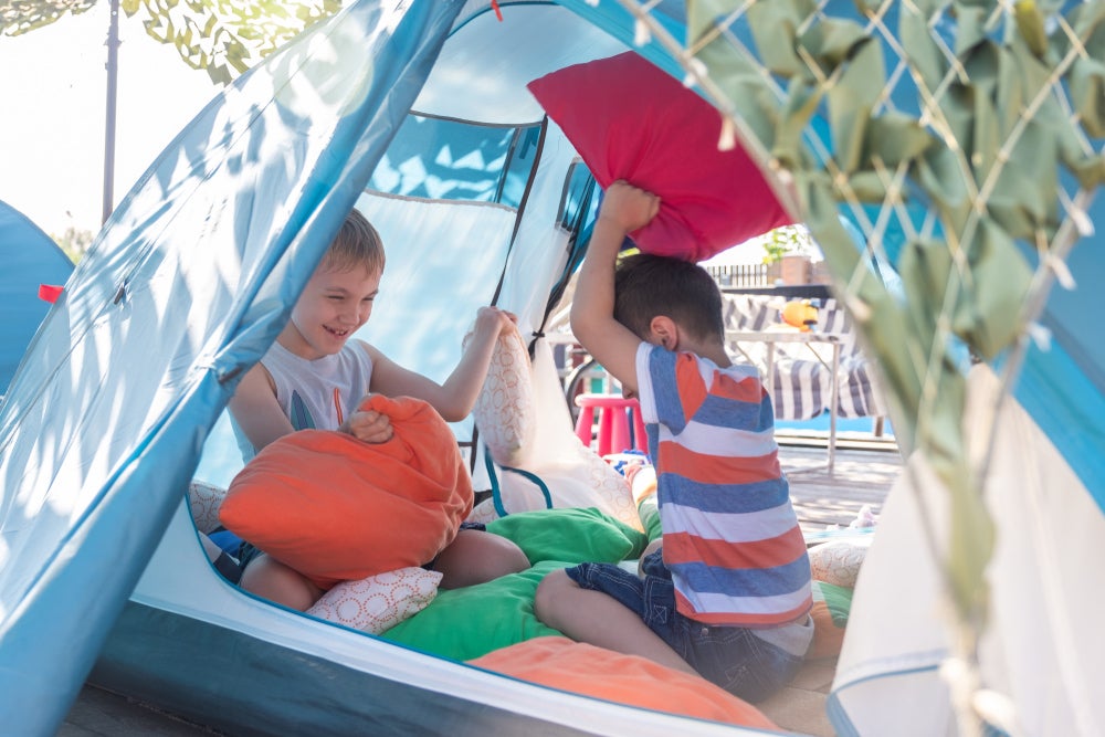 two kids playing in a tent in the daytime