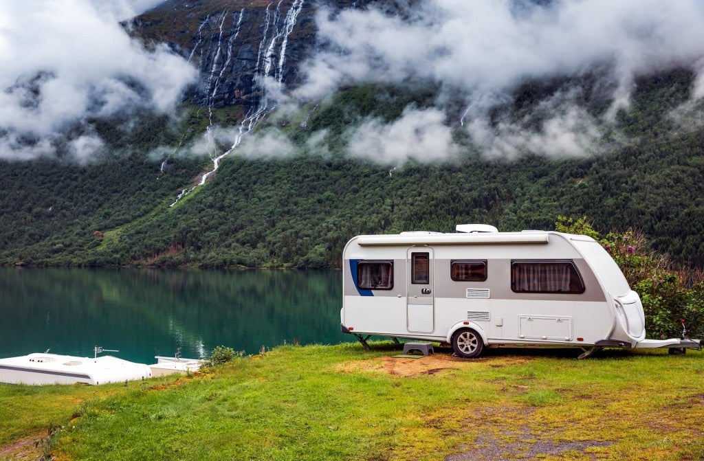 RV next to lake with hill and waterfall in background