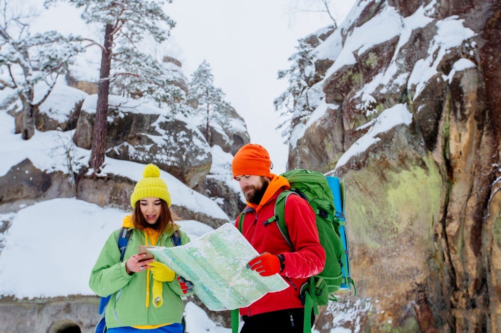 Couple reading a map while hiking in the winter.