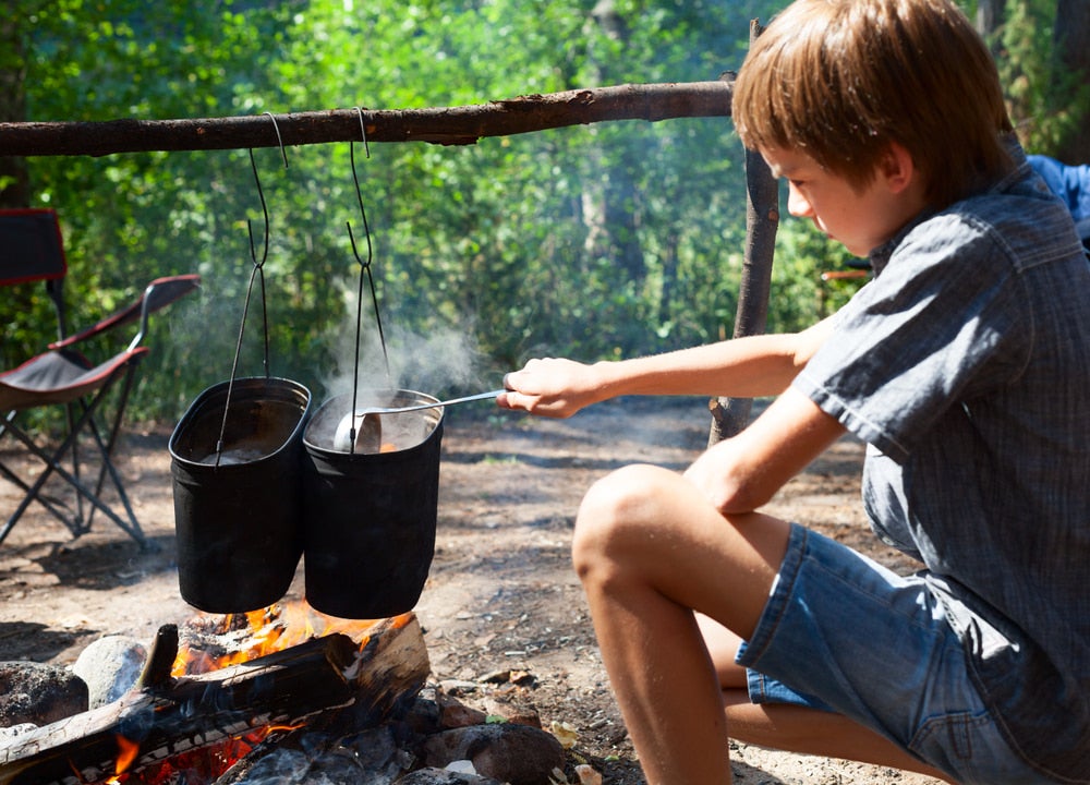 a kid cooking over a campfire at a campground