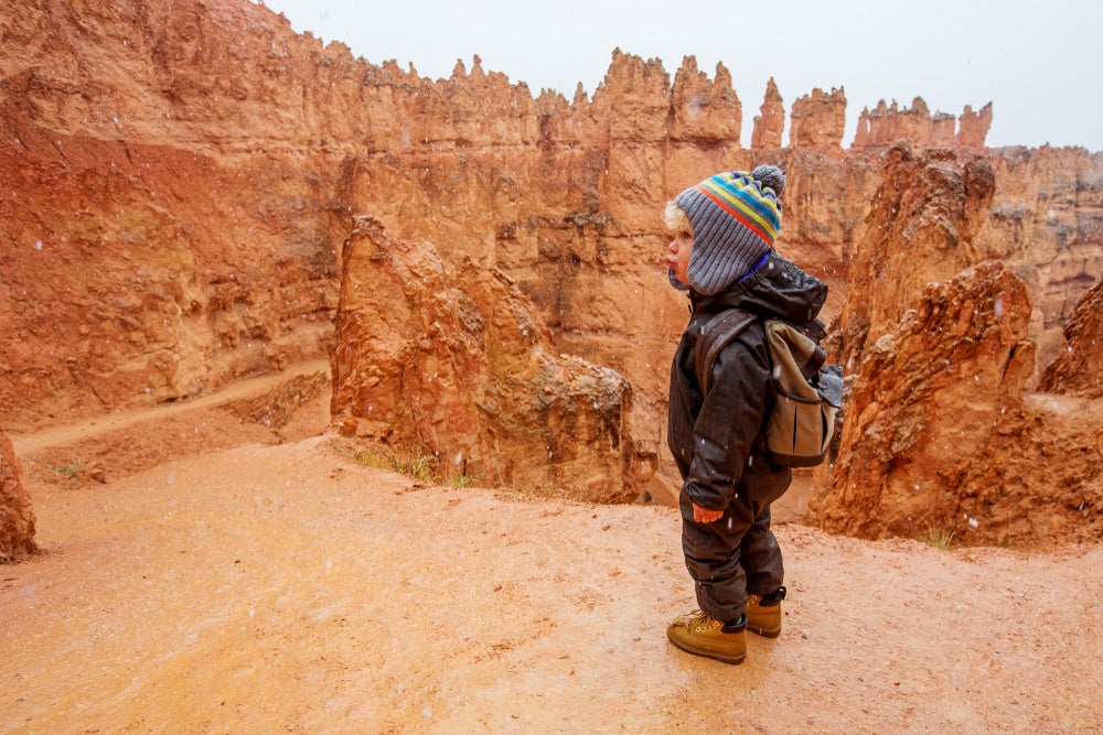 Child standing with red rocks behind him 