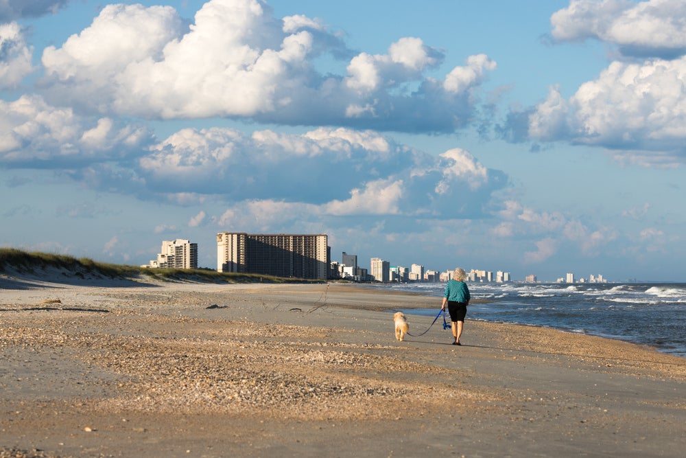 a woman walking a dog on myrtle beach in south carolina