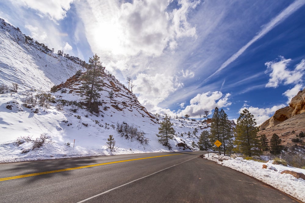 a wet road through a snowy zion national park in winter