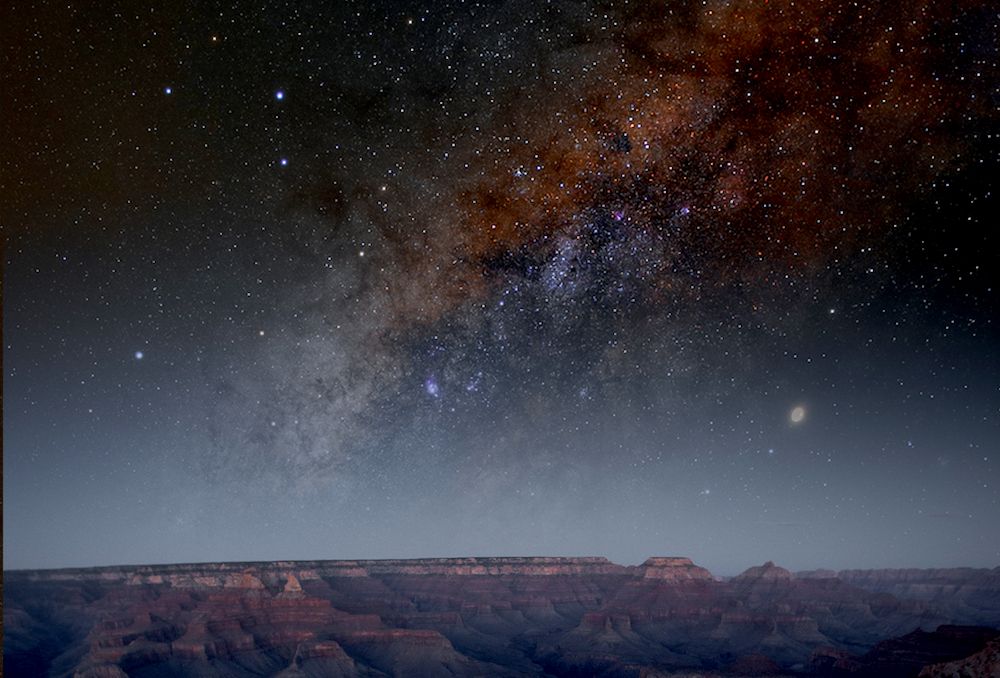 wide angle of the grand canyon at night displaying warm-toned galaxy in the sky above