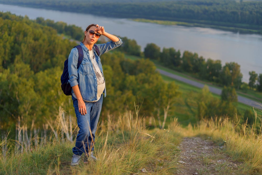 Pregnant woman wiping sweat while on the trail.