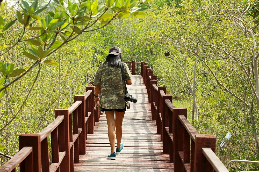 Woman walking on bridge holding camera 