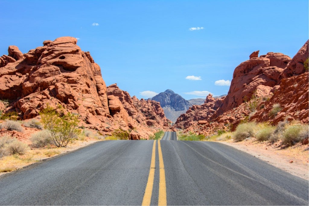 a highway traveling between red rock canyons in nevada