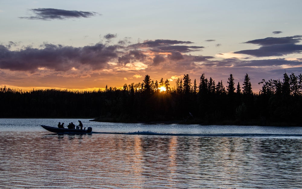 a boat of three men fishing at sunset on the kenai river in alaska