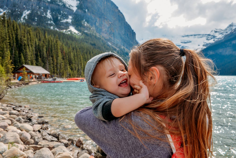 Baby and mother hugging with mountains in background 