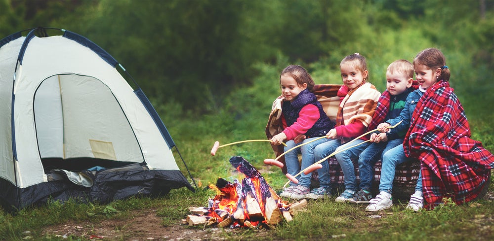 four kids cooking food over the fire