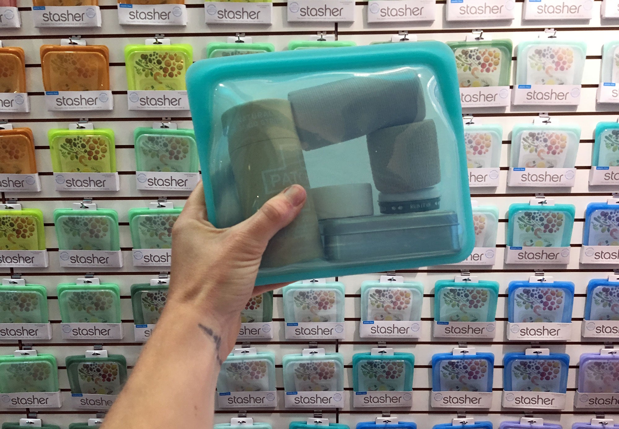 hand holding a full stasher bag in front of product display at outdoor retailer