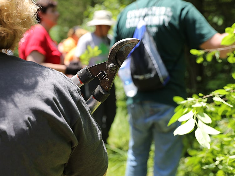 a woman holding plant shears around a group of trail volunteers