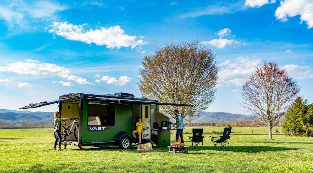 campers gather around sylvan sports modular camper in a field on a clear day