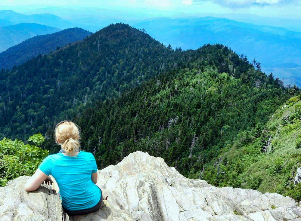 Woman sitting on rocks overlooking mountains