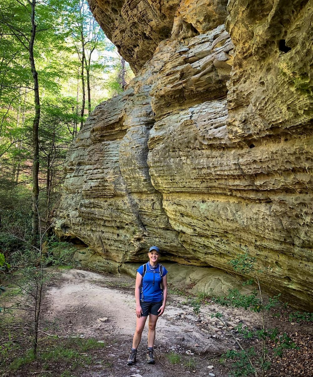 Woman standing next to rocks with forest in background 