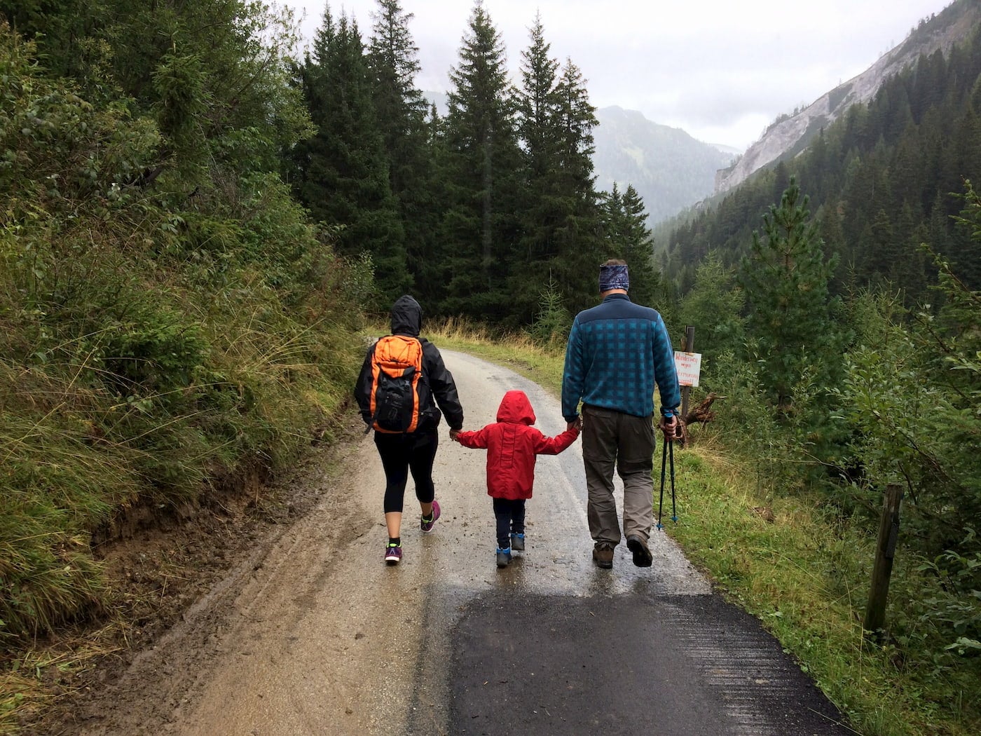 Parents holding infants hands while hiking.