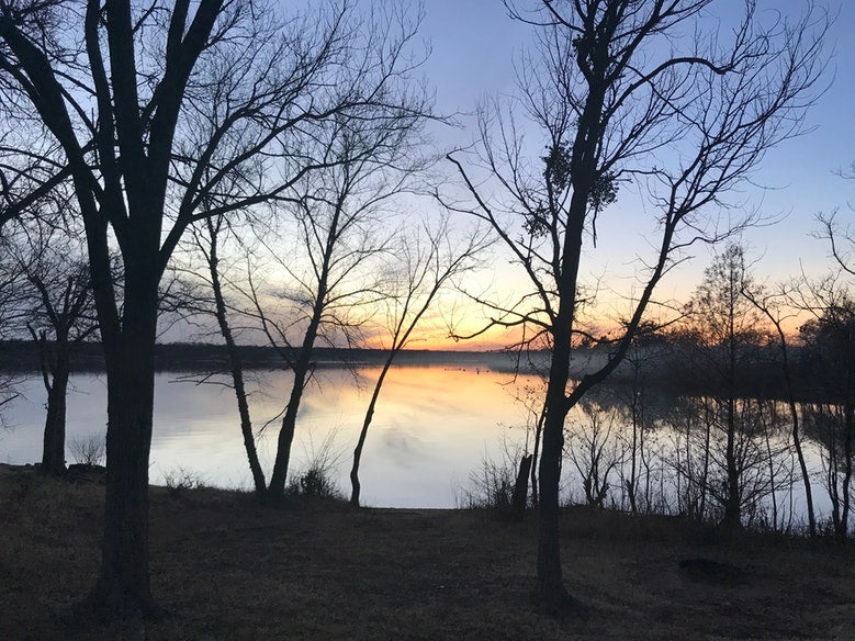 blue and orange skies visible over calm Arcadia Lake in Oklahoma, photo from a camper on The Dyrt