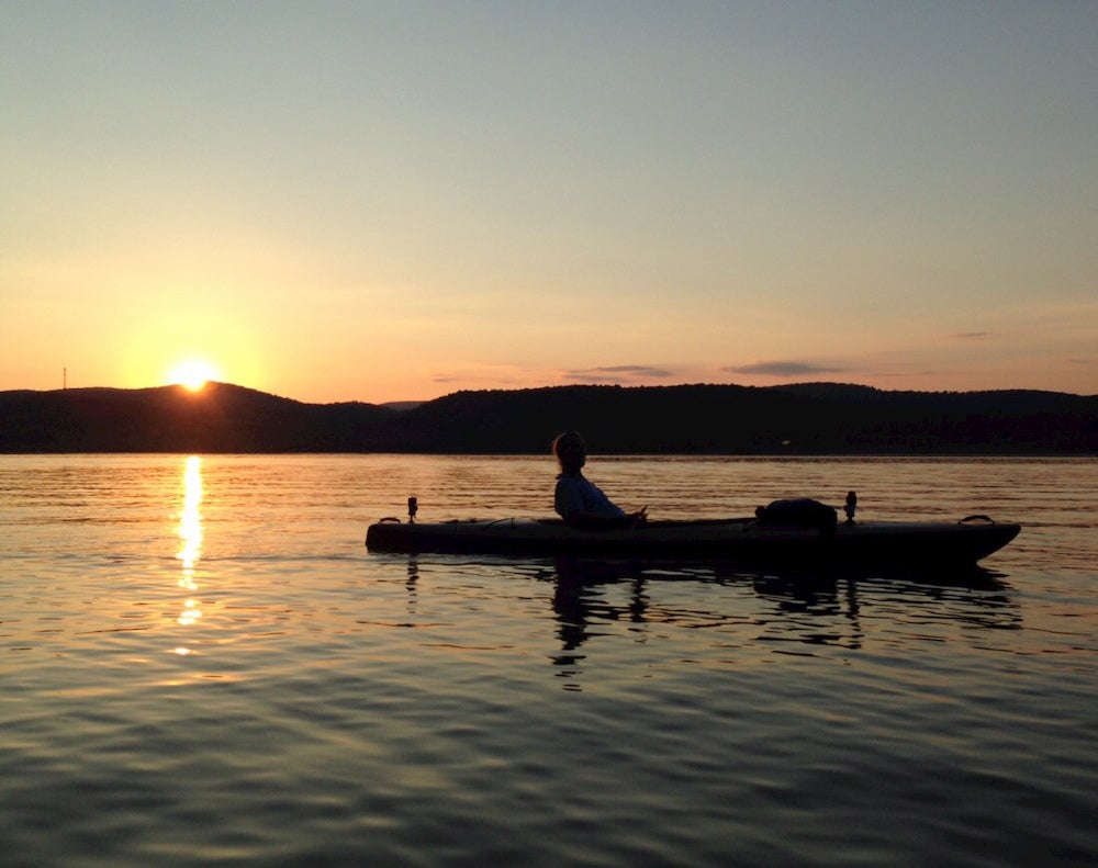 Woman floating on lake at sunset. 