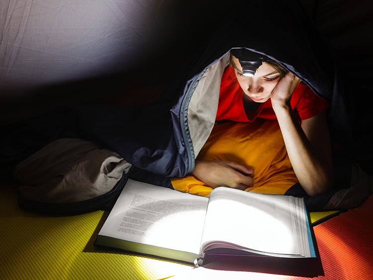 child reading in tent with headlamp