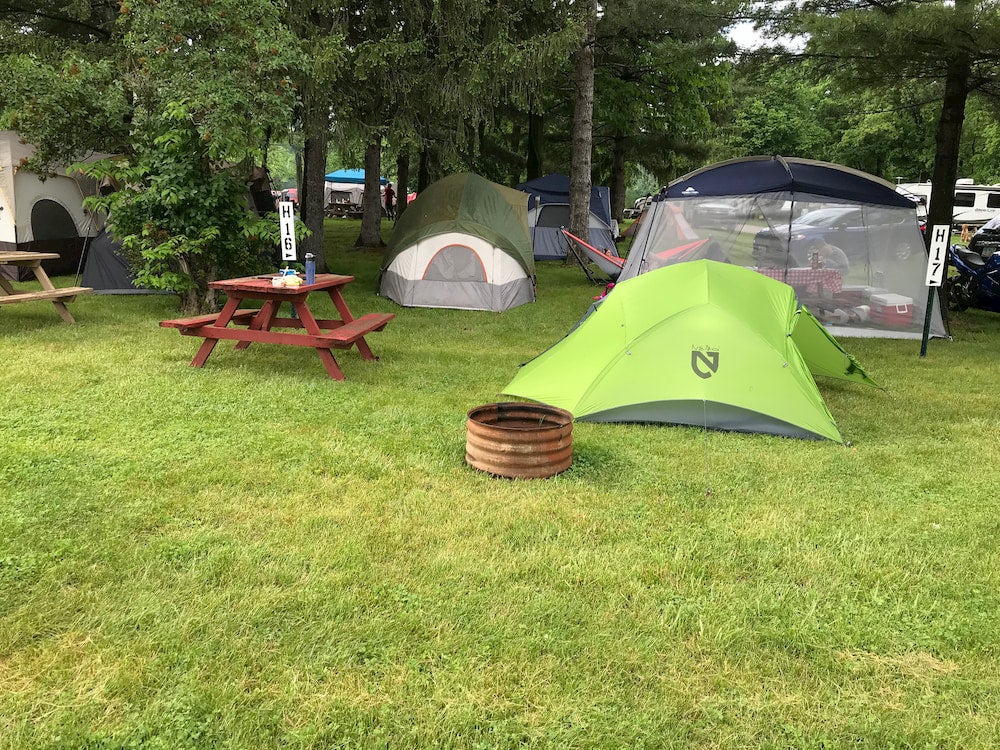 Green tent and other tents on campsite with trees in background 