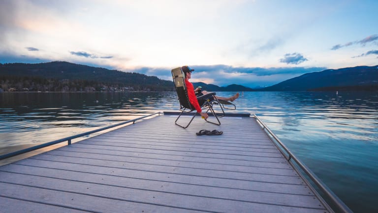 a man sitting in a chair on a dock at dusk