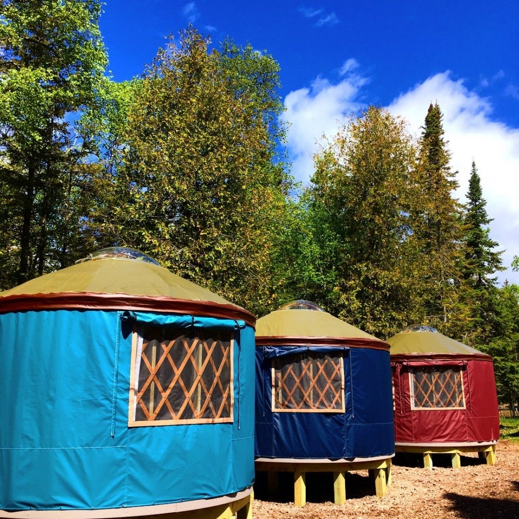 three bright colored yurts in the woods