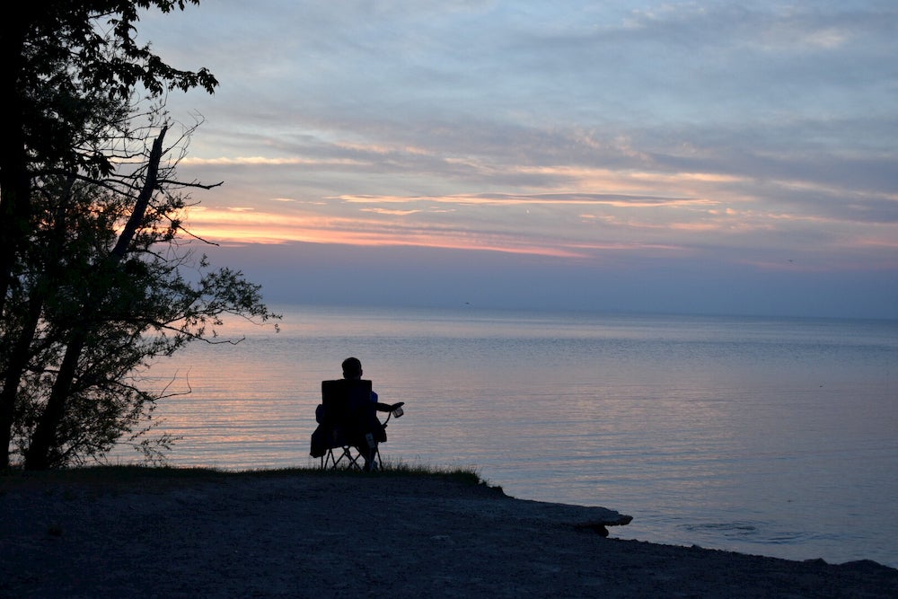 Man sitting at lake at sunset 