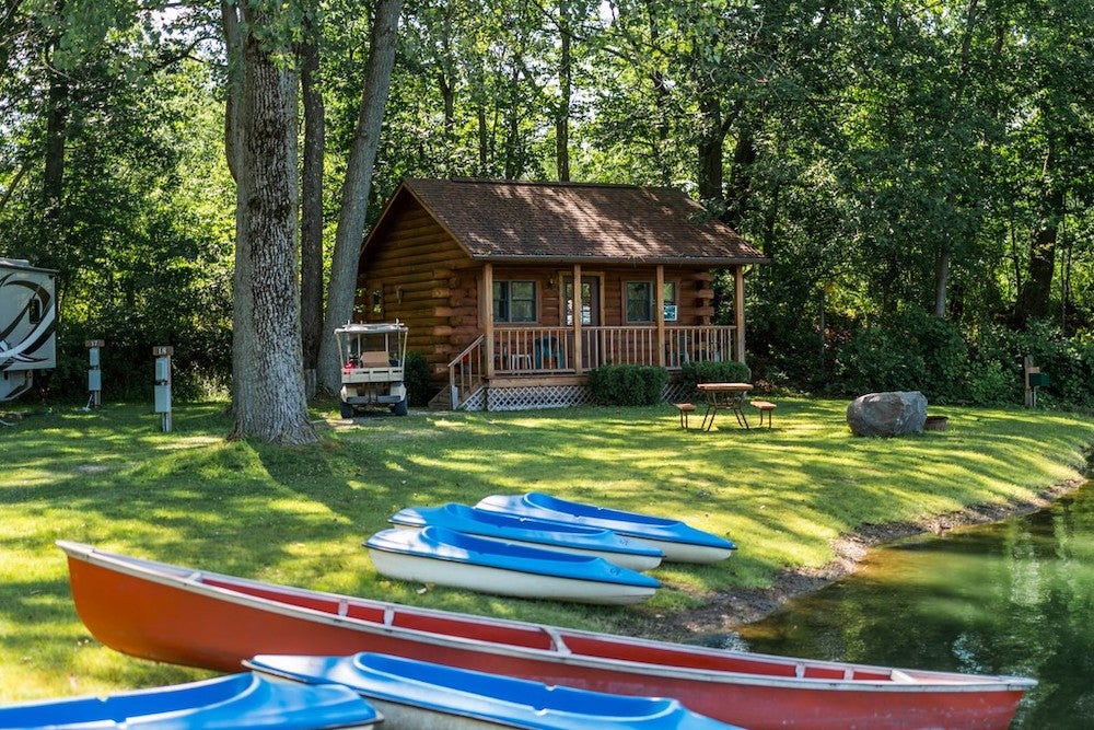 small canoes on lake with cabin in background 