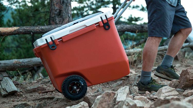 a man tows a rolling cooler on a trail
