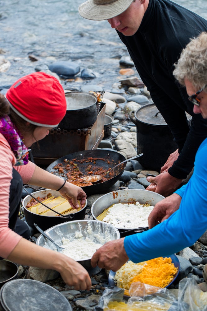 People cooking lasagna in Dutch ovens 