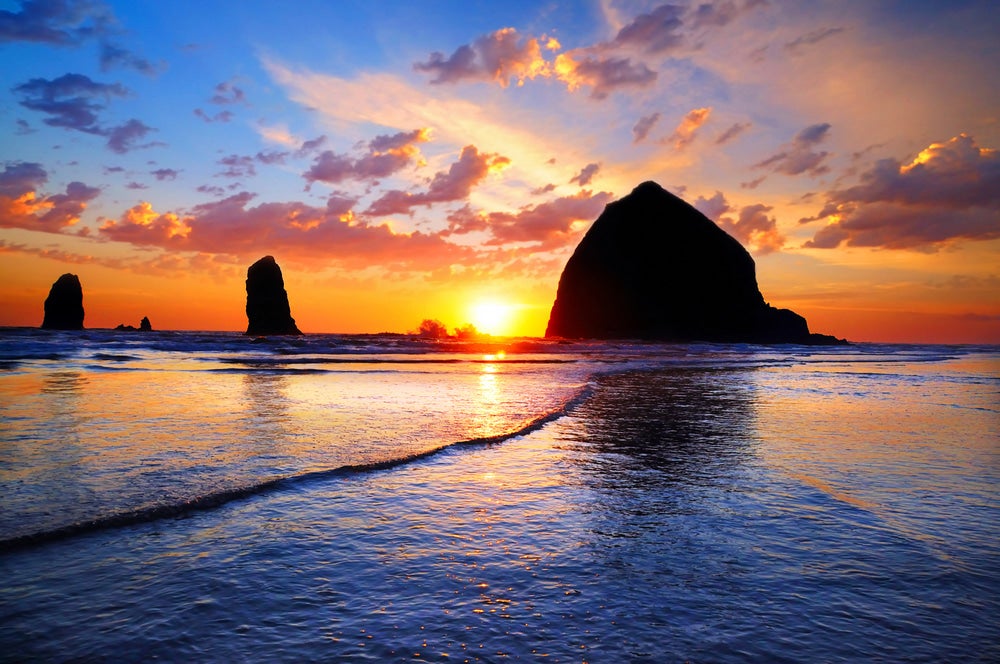 Haystack rock at beach with sunset in background 