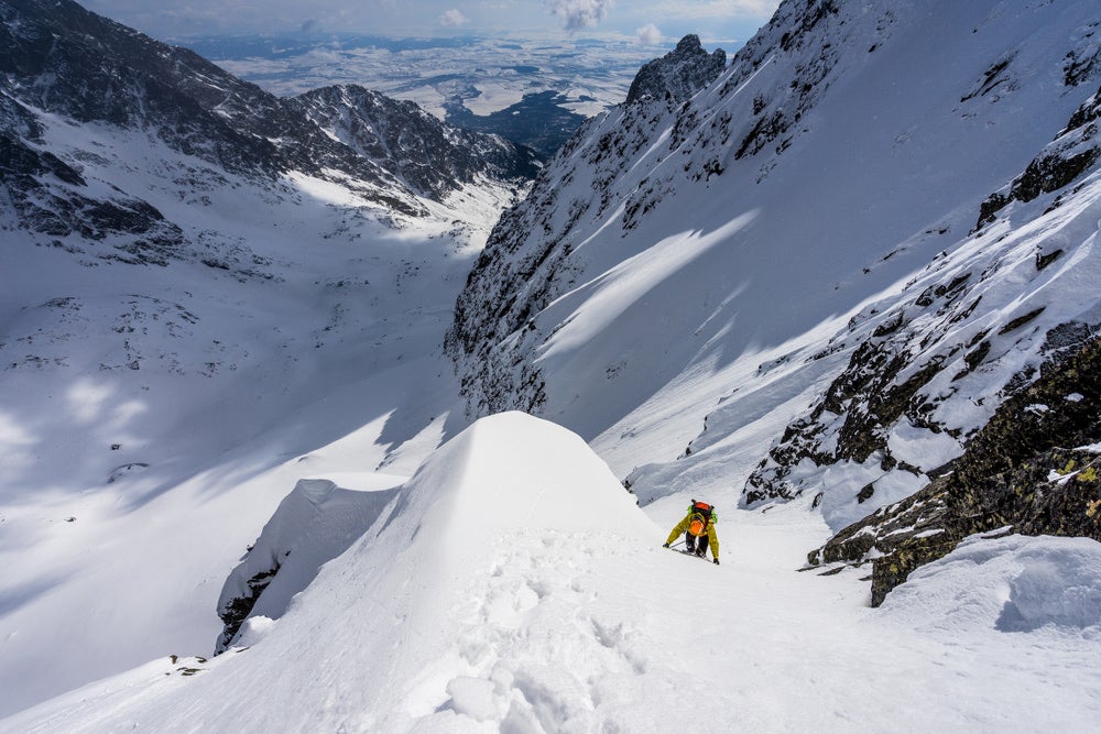 a man climbing a snow bank on a mountain in france