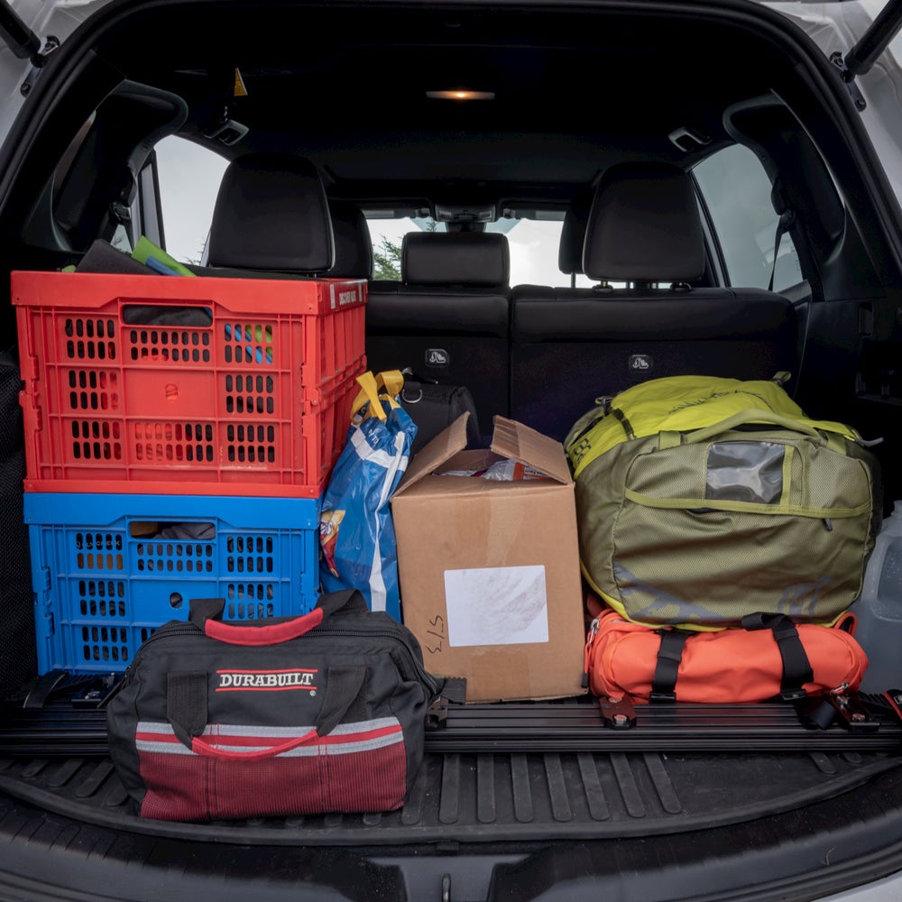 Car packed up with camping bins and a duffel bag.