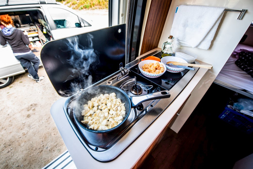 Chicken cooking in a frying pan on an RV stove.