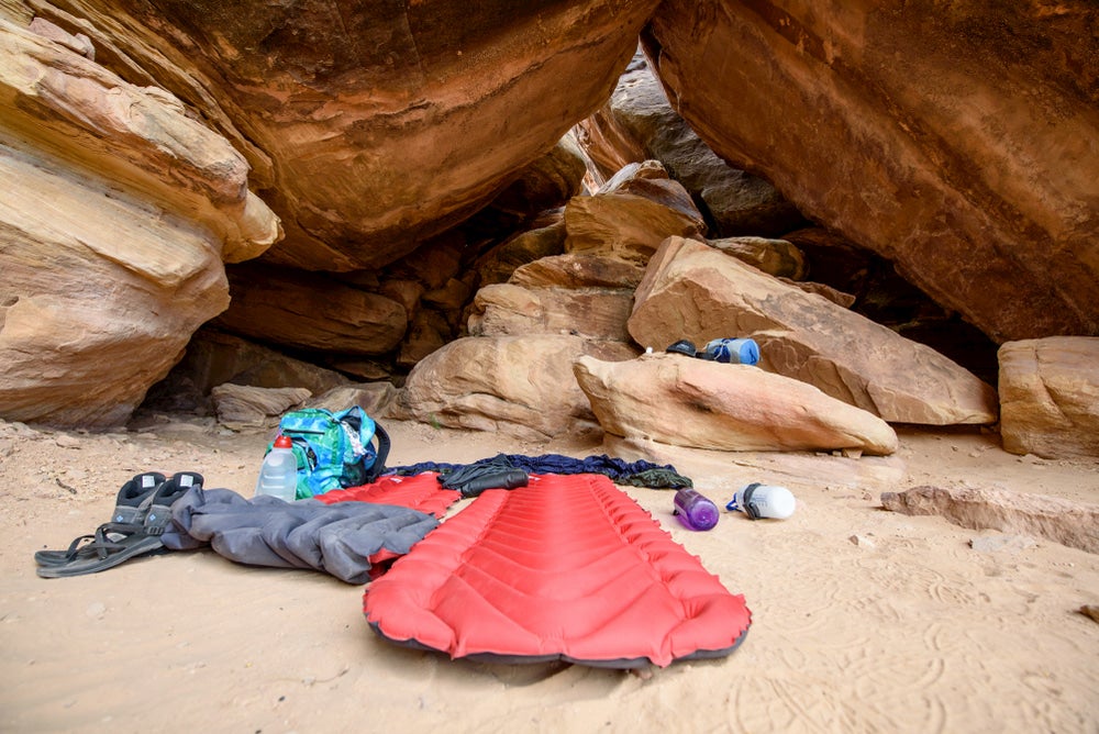 Sleeping pad and gear setup below rock formation.